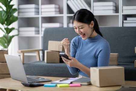 Photo for Asian woman online store business owner, online shop owner working from home, posting products for sale on website and accepting orders and packing products for customers with private courier service. - Royalty Free Image
