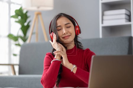 Asian beautiful woman sits in living room, she is college student listening to relaxing music, studying from home, online learning. University student concept.