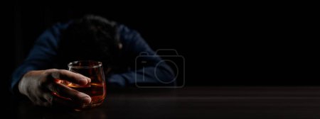 Foto de Un hombre bebe whisky, un hombre de negocios alivia el estrés del trabajo sentado y bebiendo whisky en la oficina después de terminar un trabajo duro, un hombre borracho. Concepto de consumo de alcohol. - Imagen libre de derechos