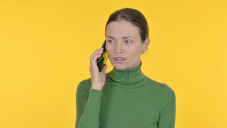 Téléchargez les photos : Jeune femme parlant au téléphone sur fond jaune - en image libre de droit