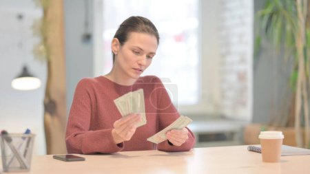 Téléchargez les photos : Jeune femme comptant des dollars au travail, calculs - en image libre de droit