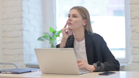 Téléchargez les photos : Penser femme d'affaires ayant une nouvelle idée tout en travaillant sur ordinateur portable - en image libre de droit