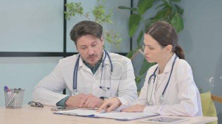 Téléchargez les photos : Male and Female Doctor Discussing Patient Medical Report - en image libre de droit