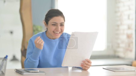 Photo for Indian Woman Celebrating Success while Reading Documents in Office - Royalty Free Image