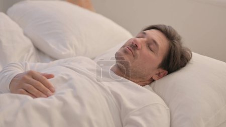 Foto de Cansado maduro adulto hombre durmiendo en cama en casa - Imagen libre de derechos