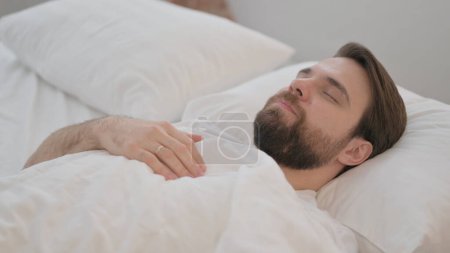 Foto de Hombre adulto joven cansado acostado en la cama para dormir - Imagen libre de derechos