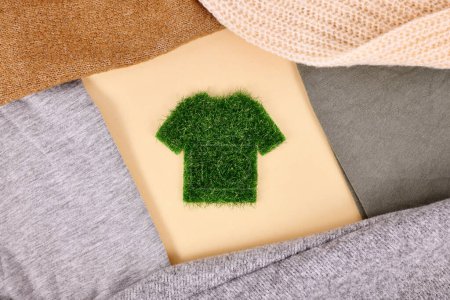 Foto de Concepto de ropa producida respetuosa con el medio ambiente con camisa hecha de hierba rodeada de suéteres - Imagen libre de derechos