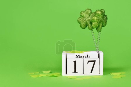 St Patricks Day holiday calendar date March 17th with shamrocks on green background with copy space