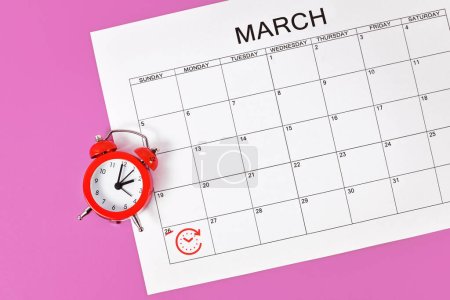 Foto de Time change concept for Central European Summer Time on March 27th with red alarm clock and calendar sheet - Imagen libre de derechos