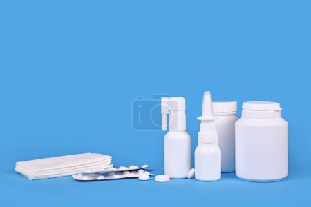 Various medication for cold and flue. Nasal spray, throat spray, pills and tissues on blue background with copy space