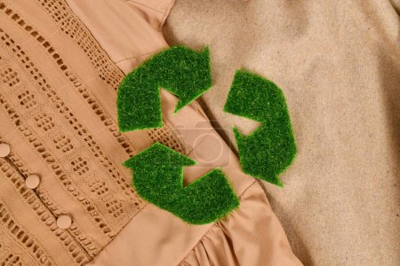 Foto de Concepto para ropa producida respetuosa con el medio ambiente con símbolo de flecha de reciclaje hecho de hierba - Imagen libre de derechos