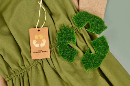 Tejido de algodón ecológico verde y beige con etiqueta 100% reciclada y símbolo de reciclaje hecho de hierba