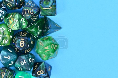 Different blue and green roleplaying RPG dice on side of blue background with blank copy space