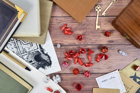 Tabletop role playing flat lay background with red RPG dices, rule books and notes on wooden background