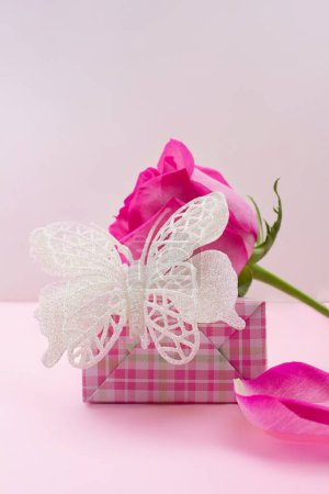 Foto de Caja de regalo con mariposa brillante, rosa y pétalo sobre fondo rosa. Cumpleaños, 8 de marzo, San Valentín, Día Internacional de la Mujer. Copiar espacio - Imagen libre de derechos