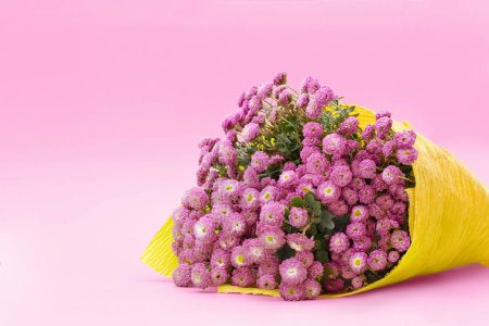 Téléchargez les photos : Bouquet of small chrysanthemums in yellow paper on pink background. Congratulation, birthday gift, international women's, mother's day. Copy space - en image libre de droit