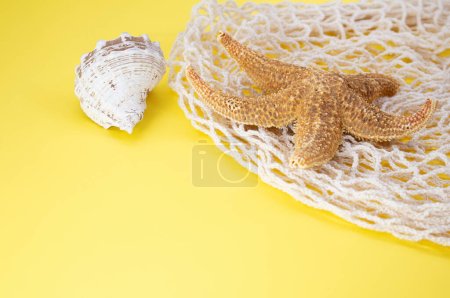 Foto de Estrella de mar, conchas con bolsa bolsa de hilo sobre fondo amarillo. Concepto de verano, vacaciones, viajes. Copiar espacio - Imagen libre de derechos