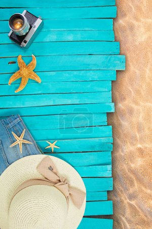 Photo for Blue pier boards or sun lounger with shorts, straw hat, starfish and camera next to sea water. Beach layout. Travel, tourism, summer background. Copy space - Royalty Free Image