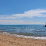 Seascape with wooden gray pier leading to sea, ocean, lake with blue sky. Travel concept, seascape, nature. Issyk-Kul, Kyrgyzstan. Copy space