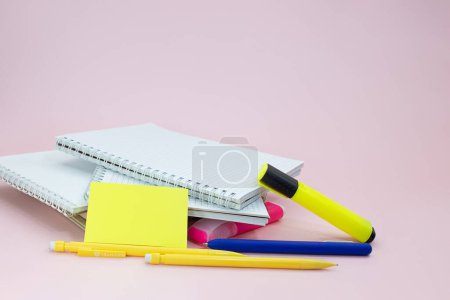 Foto de Cuadernos con bolígrafos, marcadores y pegatinas sobre fondo rosa. A la reunión de negocios de la escuela. Copiar espacio - Imagen libre de derechos