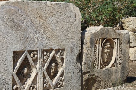 Historical stone bas-relief with carved faces in ancient city of Myra on sunny day outdoor. Dead civilization. Ruins of rock tombs in Lycia region, Demre, Antalya, Turkiye