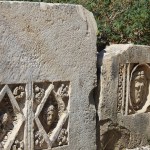 Historical stone bas-relief with carved faces in ancient city of Myra on sunny day outdoor. Dead civilization. Ruins of rock tombs in Lycia region, Demre, Antalya, Turkiye