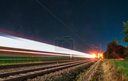 Foto de Senderos ligeros de un tren de conducción rápida por la noche con las estrellas de la Vía Láctea.. - Imagen libre de derechos