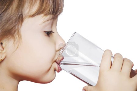 Téléchargez les photos : L'enfant boit de l'eau dans un verre d'isolat. Concentration sélective. Enfant.. - en image libre de droit