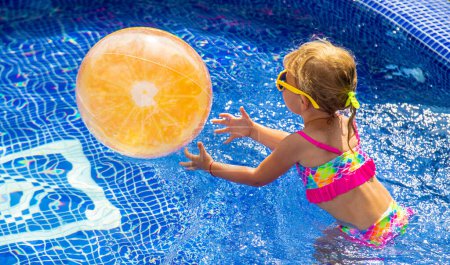 Téléchargez les photos : Un enfant joue avec une balle dans la piscine. Concentration sélective. Enfant.. - en image libre de droit