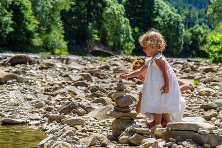 Photo for Children throw stones into the river. Selective focus. Kid. - Royalty Free Image