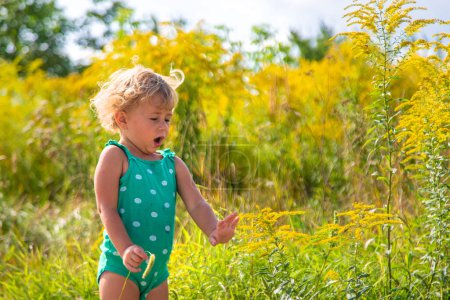 Téléchargez les photos : Un enfant est allergique à la floraison de l'herbe à poux dans le parc. Concentration sélective. Nature. - en image libre de droit