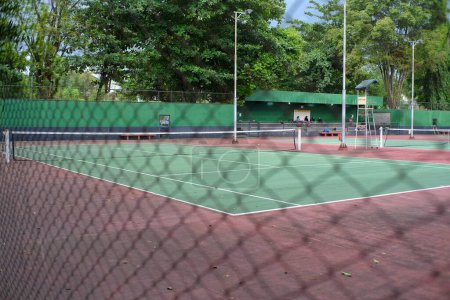 Photo for A tennis court left empty without a game behind a wire mesh guardrail - Royalty Free Image