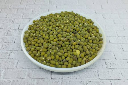 Pile of mung beans or Vigna Radiata in a white plate. This food source containing high levels of vegetable protein is rich in fiber and prebiotics.