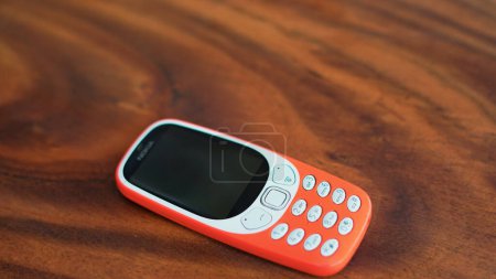 Foto de Un teléfono con teclado con botones aislados sobre fondo negro. Teléfono celular viejo con pantalla negra. Primer plano de un móvil naranja de 2g y 3g en la India. Tecnología y concepto social. - Imagen libre de derechos