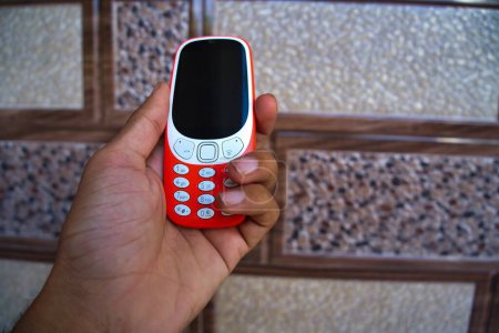 Foto de Mano sosteniendo un teclado del teléfono móvil aislado en el fondo de textura. Mini botones del teléfono celular y pantalla negra y las teclas de marcación en las manos. Antiguo Nokia 2g, teléfono inteligente 3g - Imagen libre de derechos