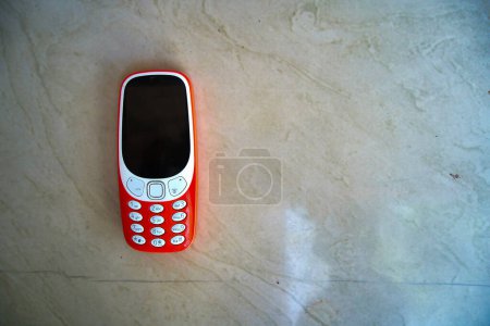 Foto de Un teclado de teléfono móvil aislado en el fondo de textura. Mini botones del teléfono celular y pantalla negra y las teclas de marcación en las manos. Antiguo Nokia 2g, teléfono inteligente 3g - Imagen libre de derechos