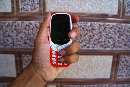 Foto de Mano sosteniendo un teclado del teléfono móvil aislado en el fondo de textura. Mini botones del teléfono celular y pantalla negra y las teclas de marcación en las manos. Antiguo Nokia 2g, teléfono inteligente 3g - Imagen libre de derechos