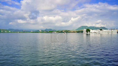 Téléchargez les photos : Lac Pichola avec ciel nuageux et collines aravali fond à Udaipur, Rajasthan, Inde. Un lac artificiel populaire pour l'équitation en bateau parmi les touristes. Voilier décoré. Ville des lacs. - en image libre de droit