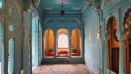 Foto de Hermosas habitaciones de color azul claro dentro del palacio de Udaipur. Rajastán, India. Colorida decoración Vista interior del Palacio de la Ciudad. Dentro de la lámpara del palacio, ventilador y marcos - Imagen libre de derechos
