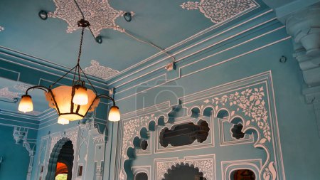 Foto de Hermosas habitaciones de color azul claro dentro del palacio de Udaipur. Rajastán, India. Colorida decoración Vista interior del Palacio de la Ciudad. Dentro de la lámpara del palacio, ventilador y marcos - Imagen libre de derechos