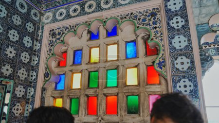 Téléchargez les photos : Palais de la ville vue de fenêtre colorée à Udaipur, Rajasthan, Inde. Les gens qui regardent la ville, à l'extérieur des fenêtres en mosaïque dans le musée. Intérieur, vue intérieure - en image libre de droit