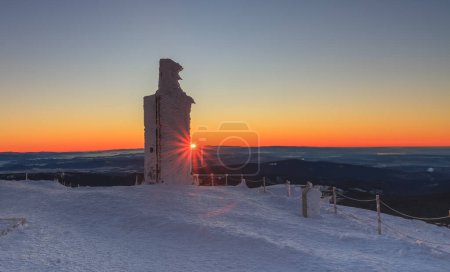Sunrise time, stone column with height quota 1603 m in snezka, mountain on the border between Czech Republic and Poland, winter morning. 