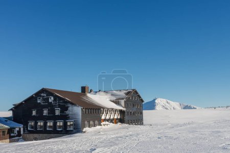 Meadow Hut is one of the highest mountain huts in Central Europe,  krkonose mountains Czech Republic. Winter morning, on background  Snezka,  mountain on the border between Czech Republic and Poland. 
