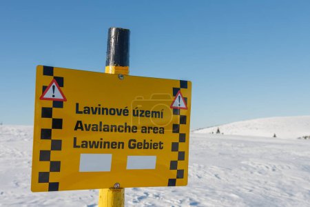 Una señal de advertencia de la zona de avalancha, valle del Elba blanco, montañas krkonose, día de invierno. Señal de advertencia de área de avalancha en checo, inglés y alemán.