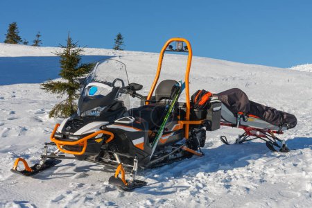 Moto de nieve con camilla servicio de rescate de montaña en frente de la casa de campo vyrovka en las montañas krkonose. 