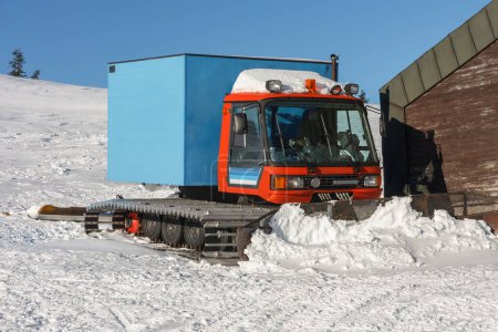 Téléchargez les photos : Red snowcat, véhicule entièrement chenillé conçu pour se déplacer sur la neige devant le chalet de ski dans les montagnes krkonose, République tchèque. - en image libre de droit