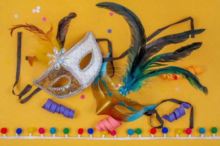 Photo for Two masks together on a yellow background adorned with confetti and colorful streamers on a yellow background - Royalty Free Image