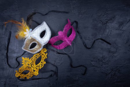 Photo for Three lively, brightly colored masks arranged together and standing out against a textured black background - Royalty Free Image