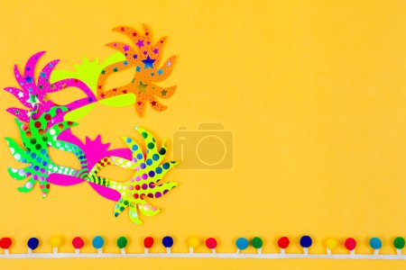 Photo for A pair of vibrant paper masks, standing alone against a sunny yellow backdrop, creating a lively and festive scene - Royalty Free Image