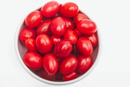 Photo for Ripe cherry tomatoes in a white bowl, on a white background. Overhead view - Royalty Free Image